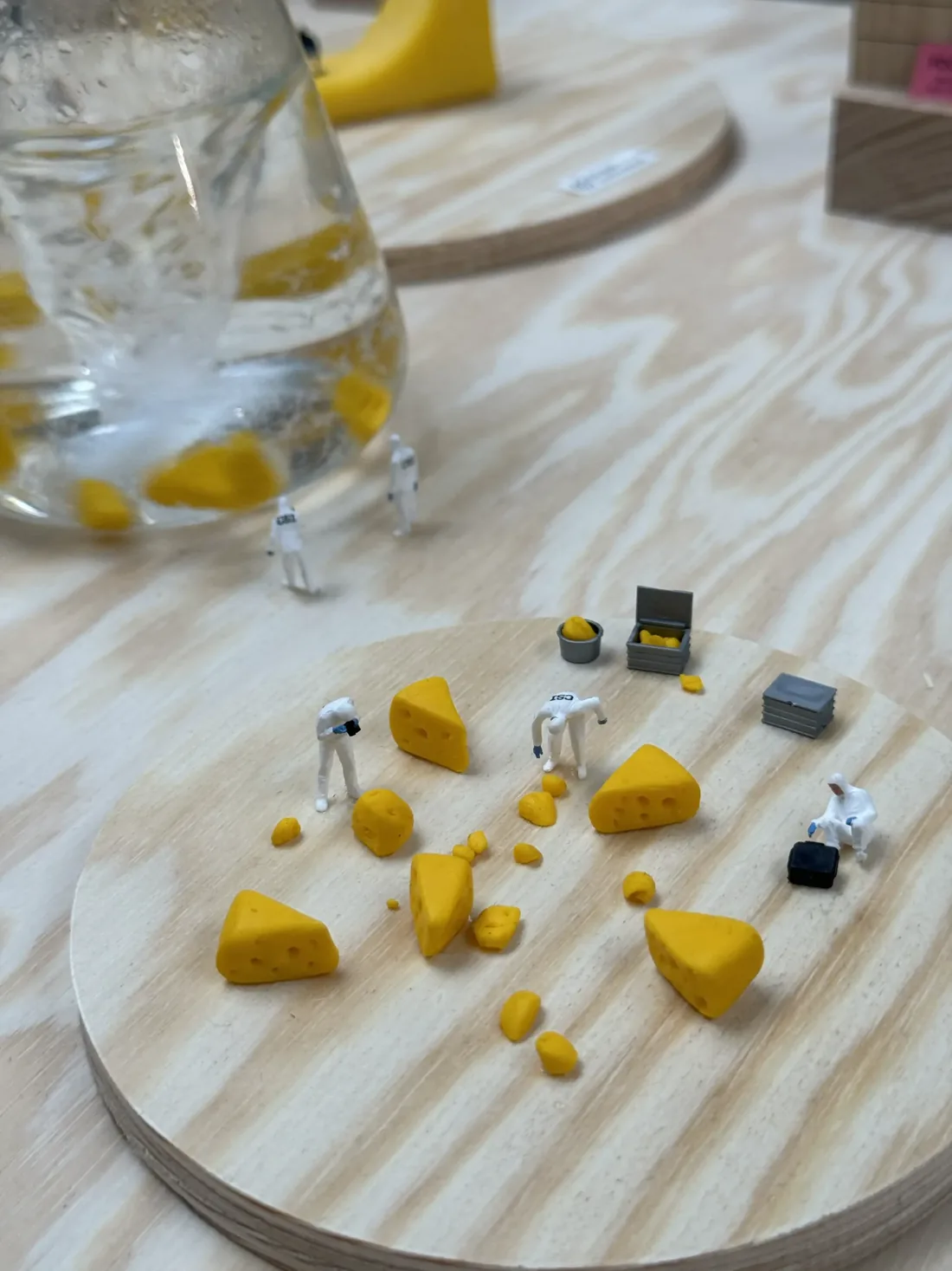 Tiny scientists studying clay cheese next to a flask where cheese swirls in water