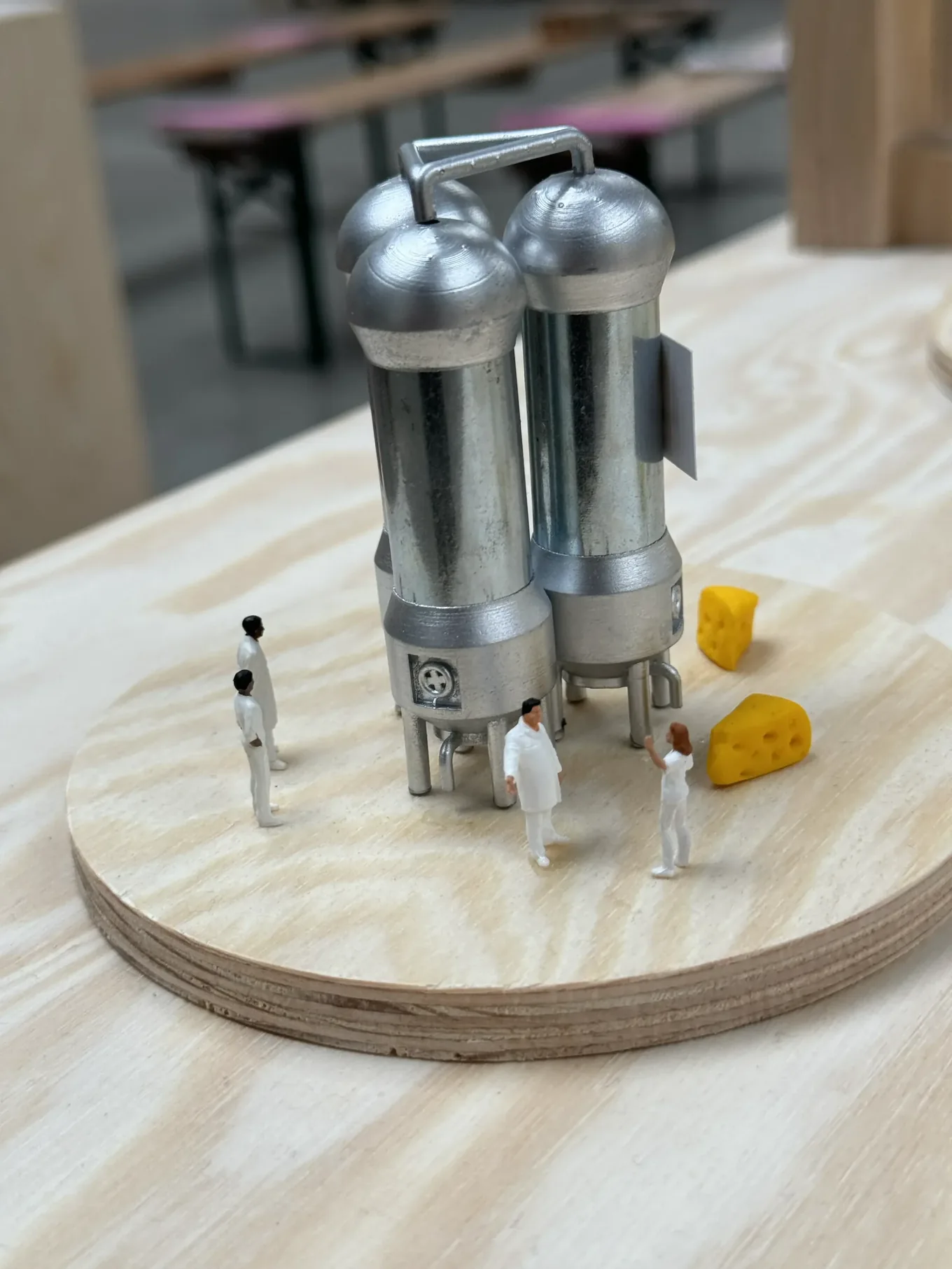 Tiny lab workers in white coats around steel fermentation tanks and pieces of cheese